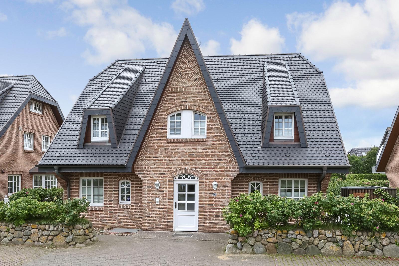 Ein zweistöckiges Haus mit rotem Ziegelmauerwerk und dunklem Schieferdach.