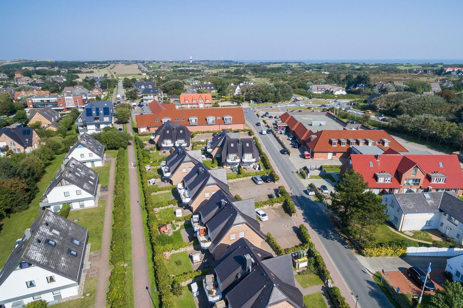 Luftbild einer Wohnsiedlung mit Häusern, Straßen und Blick auf das Meer.