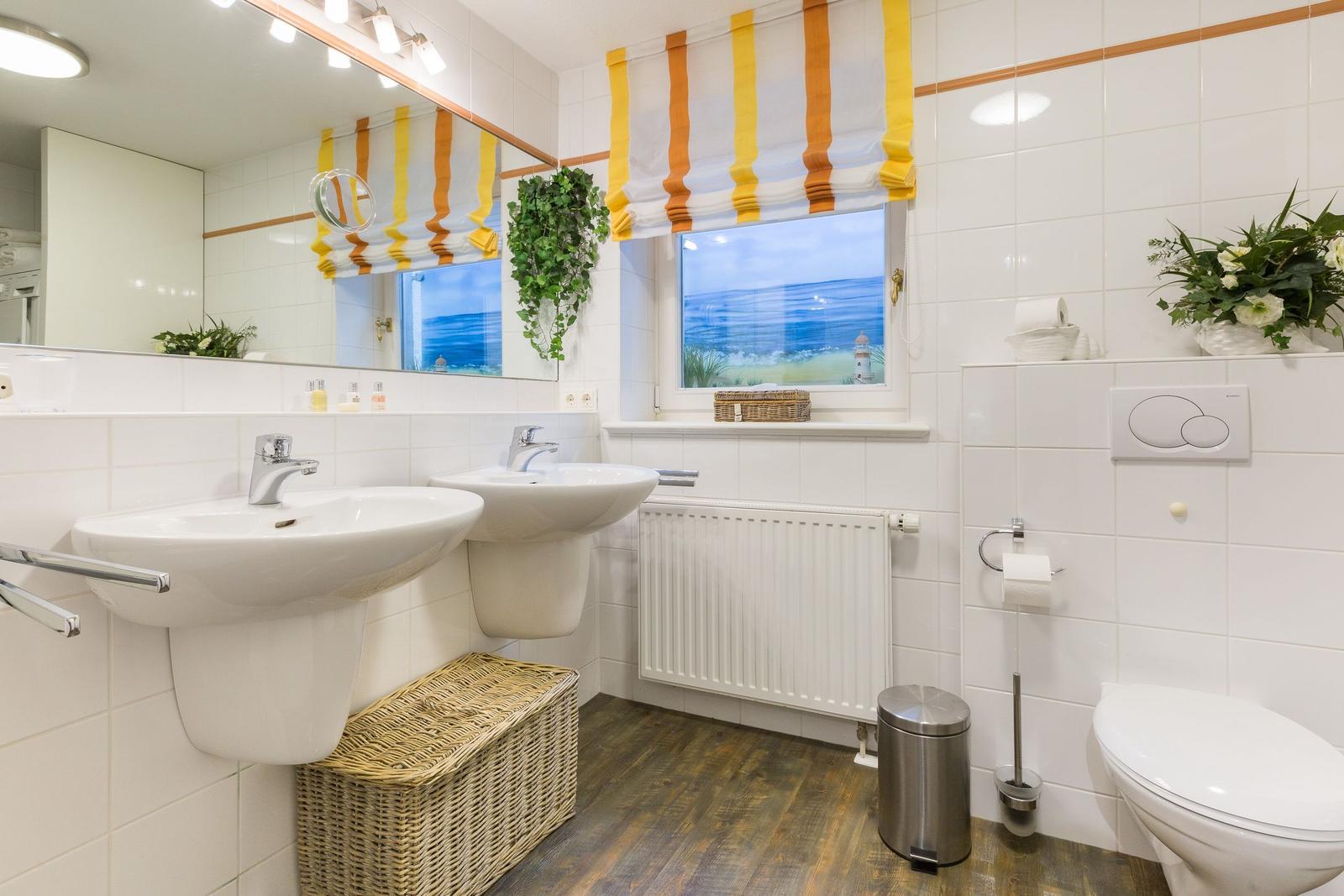 Badezimmer mit zwei Waschbecken, Toilette und Fenster mit Meerblick.