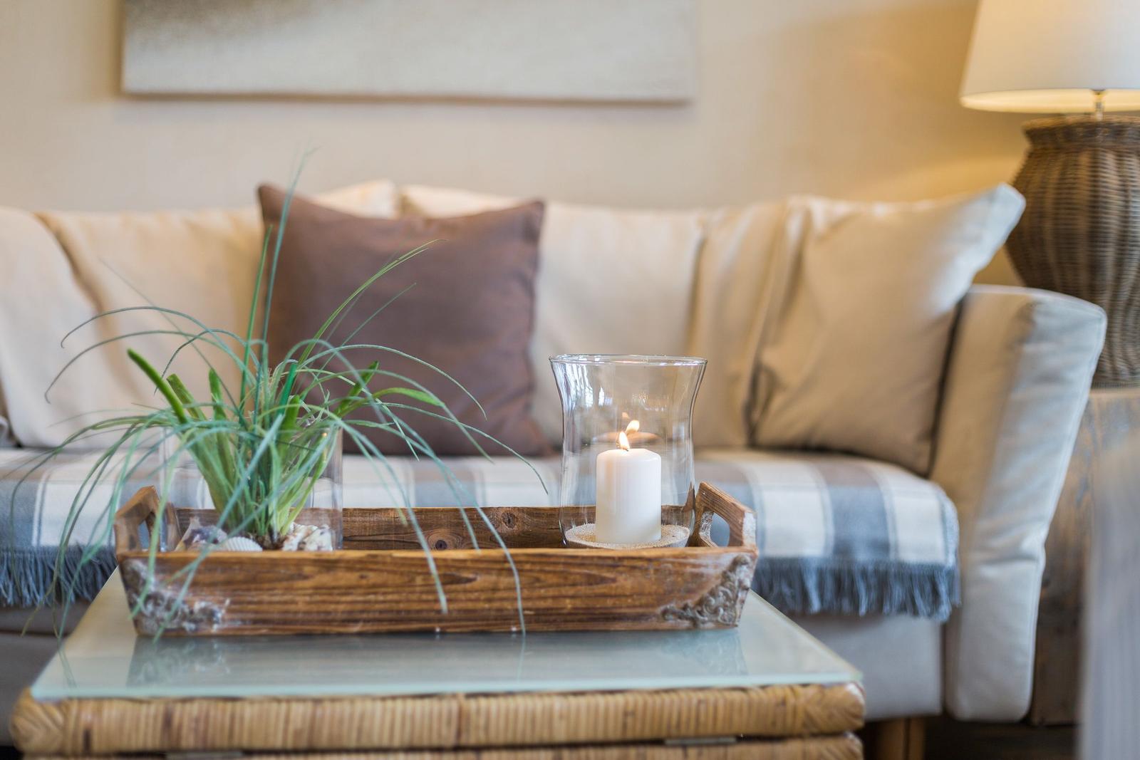 Ein Sofa mit Kissen und einem Holztablett mit Pflanze und Kerze.
