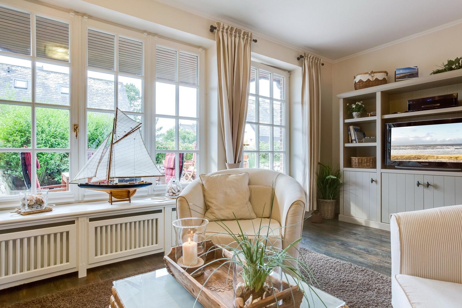 Wohnzimmer mit großem Fenster, Segelbootmodell und Fernseher.