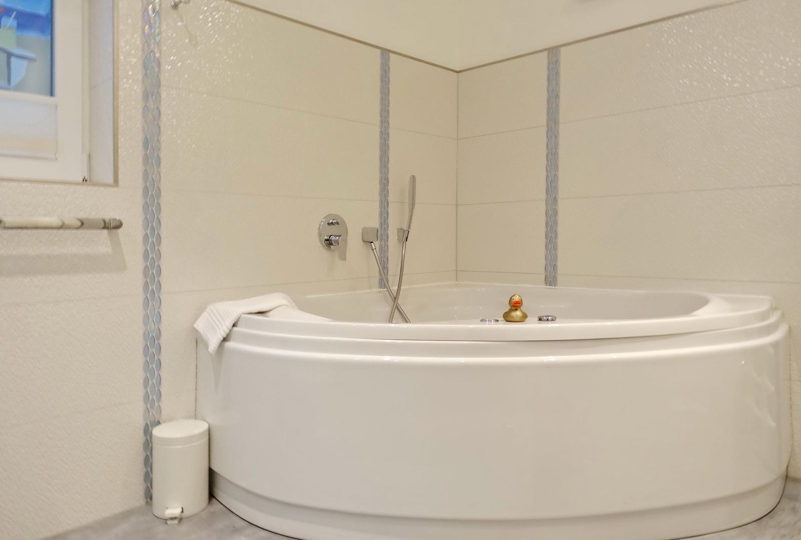 A bathtub with showerhead and yellow duck.