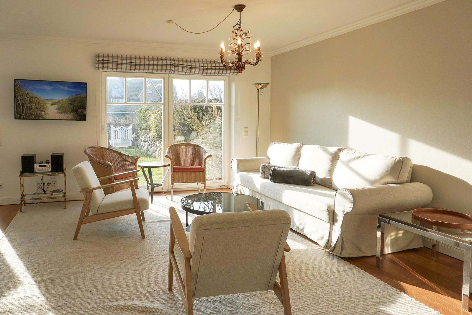 Living room with sofa, chairs, and window to outdoor terrace.