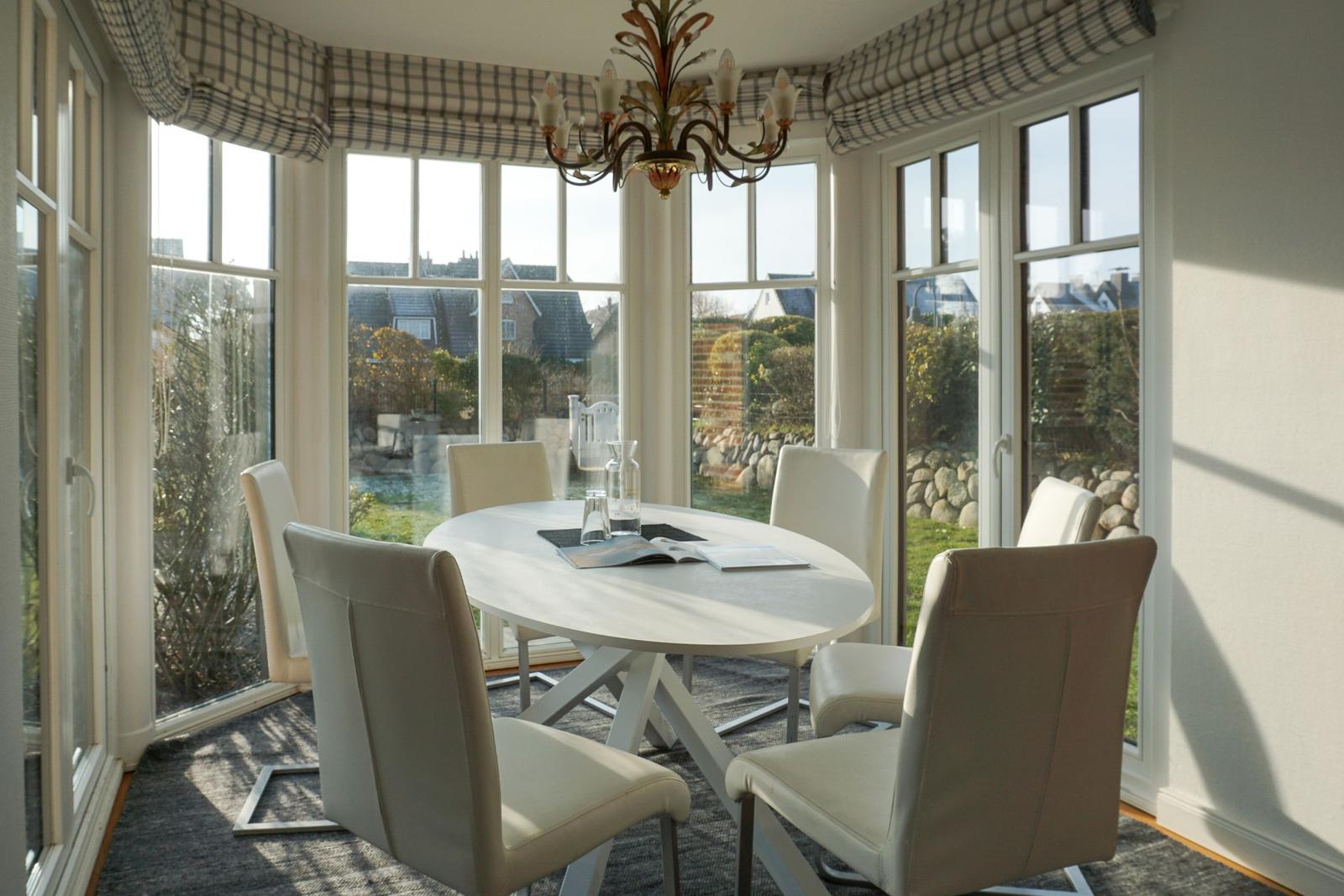 Round table with six chairs in dining room with large window view.