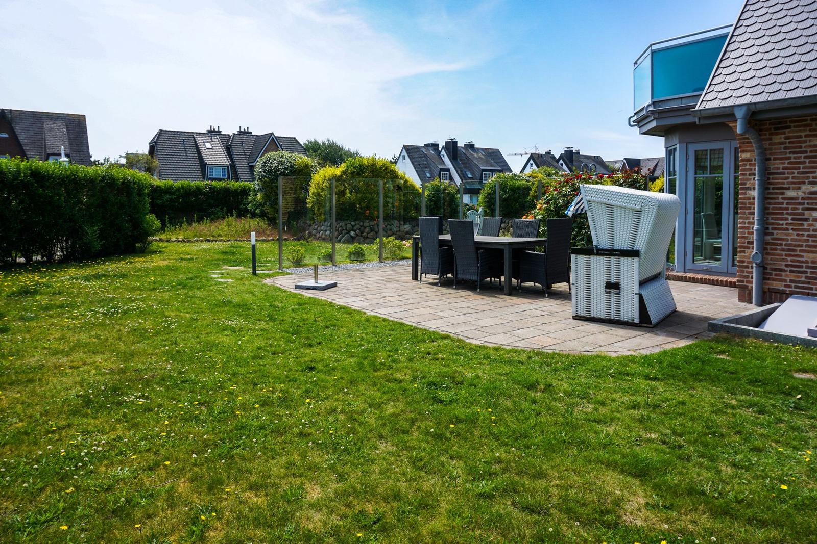 Backyard with grill area, seating group, and garden. View of residential houses.