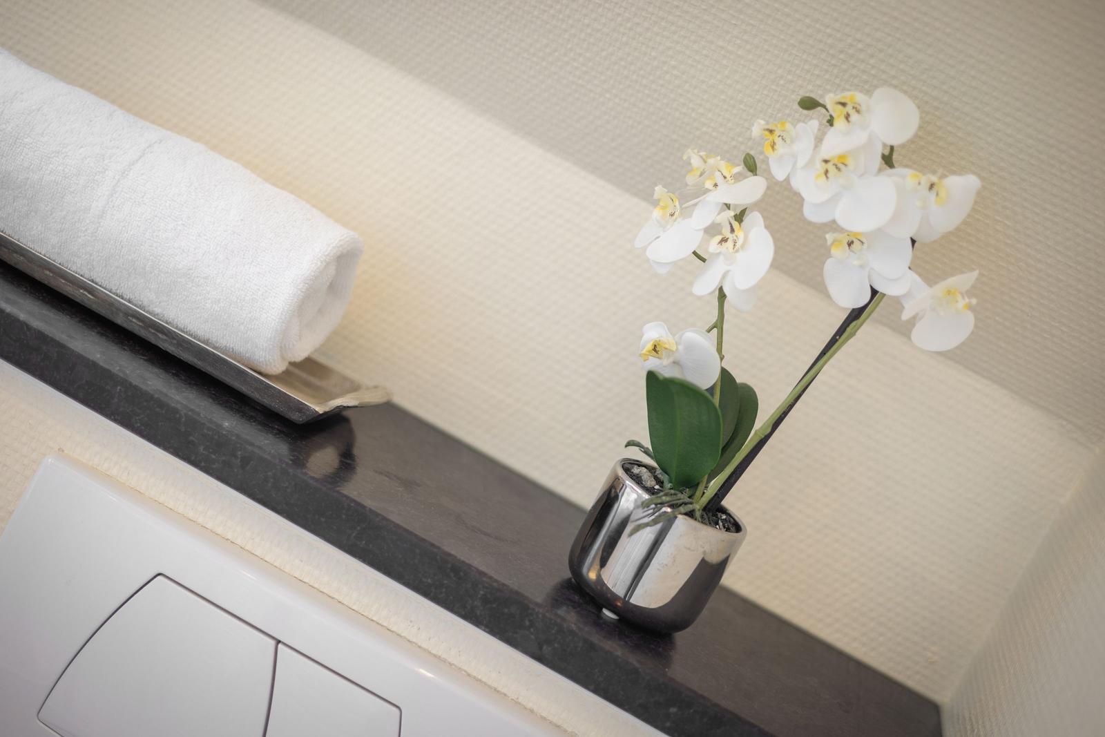 White towel roll and orchid on dark countertop edge