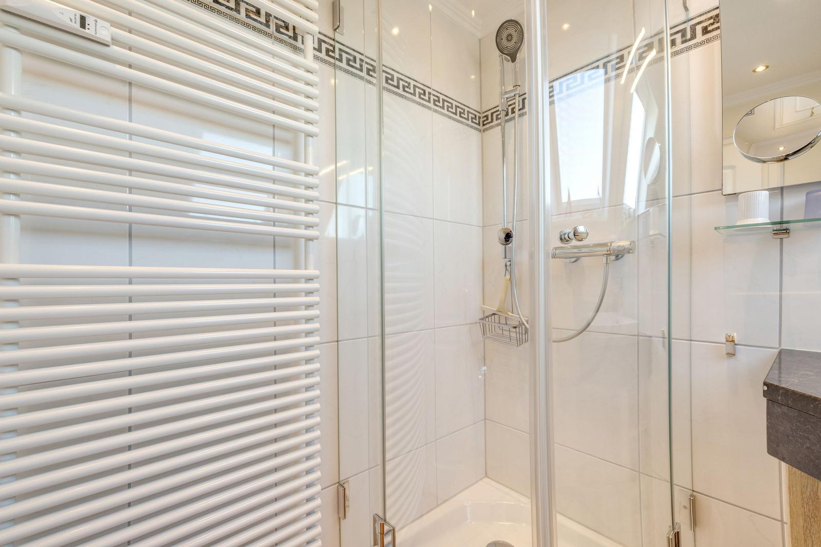 Shower with glass enclosure, heater, and mirror cabinet