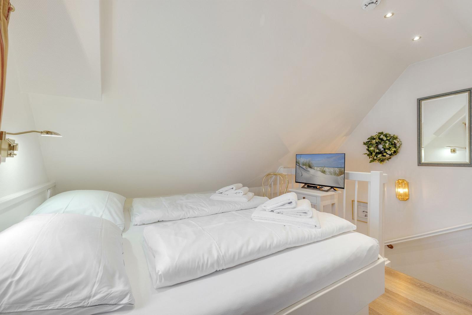 Bedroom with double bed, TV, and mirror on the wall.
