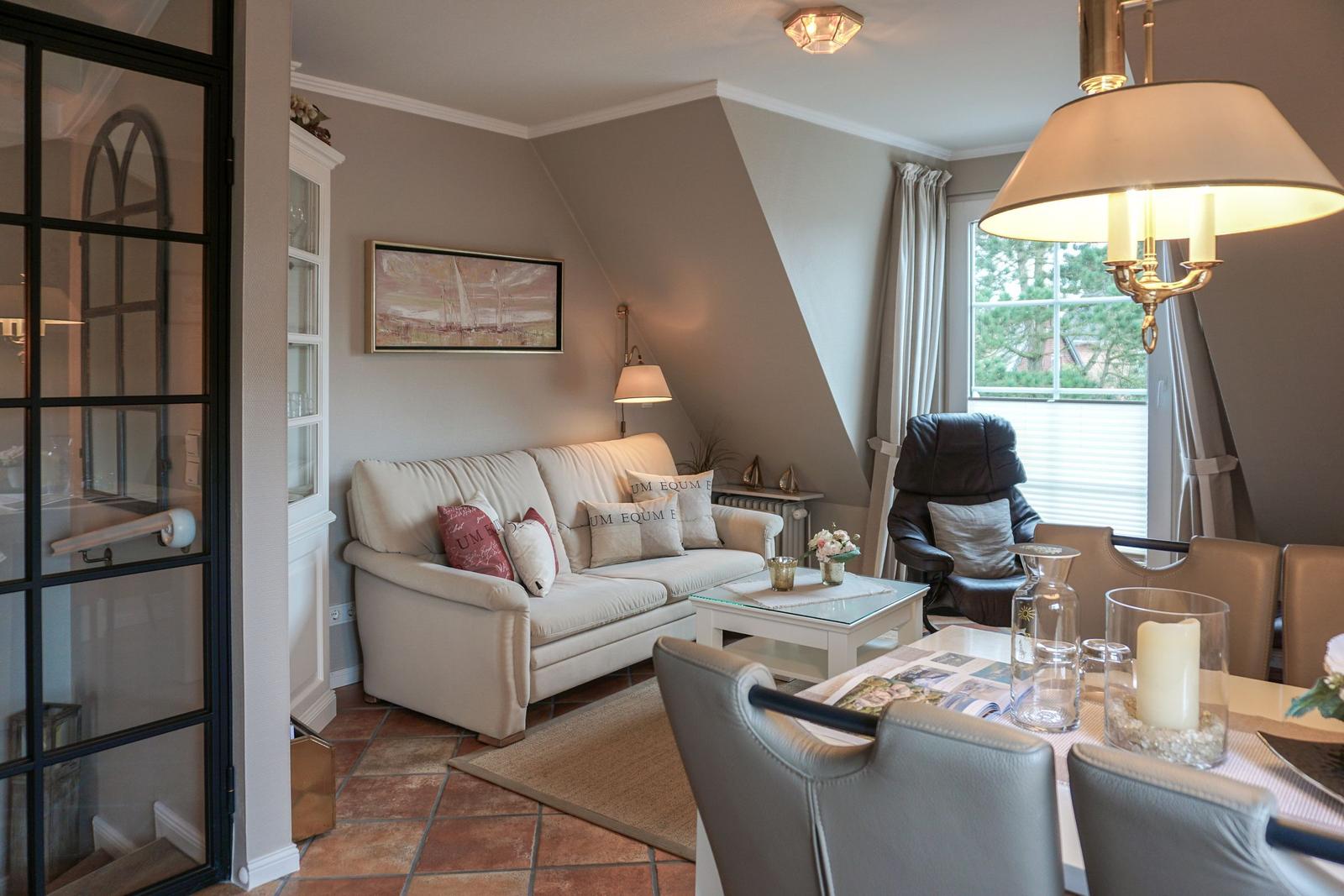 Living and dining area with sofa, table and chairs. Window with view of outside.