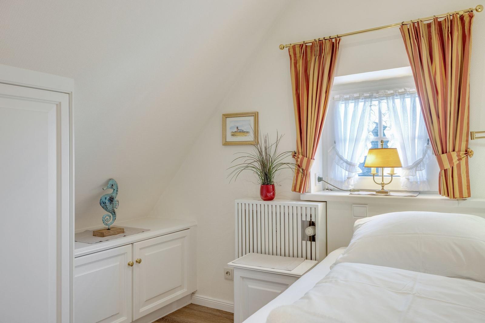 Bedroom with bed, window, curtains, and cabinet.