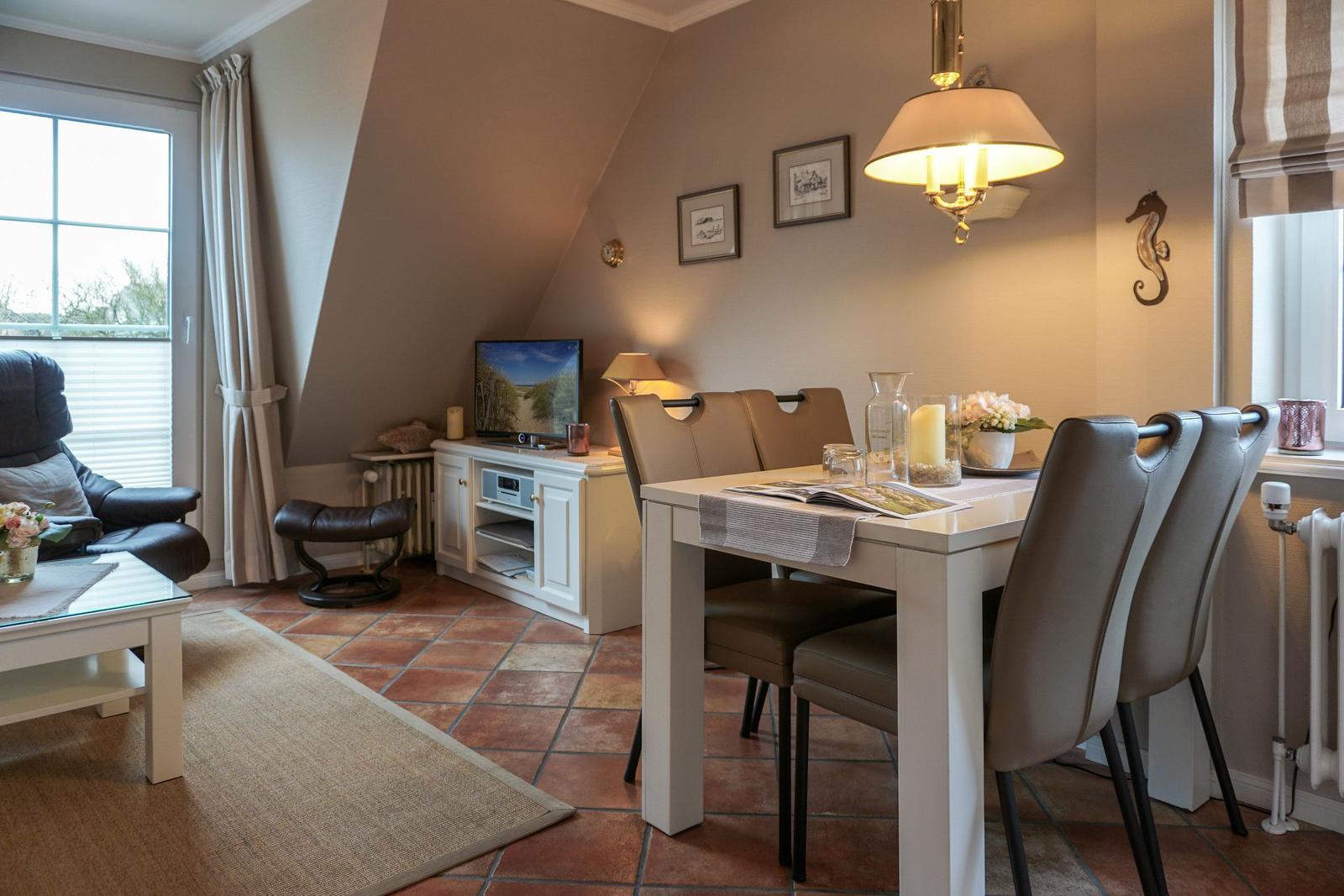 Dining area with table and chairs, TV, and seating area in attic space.