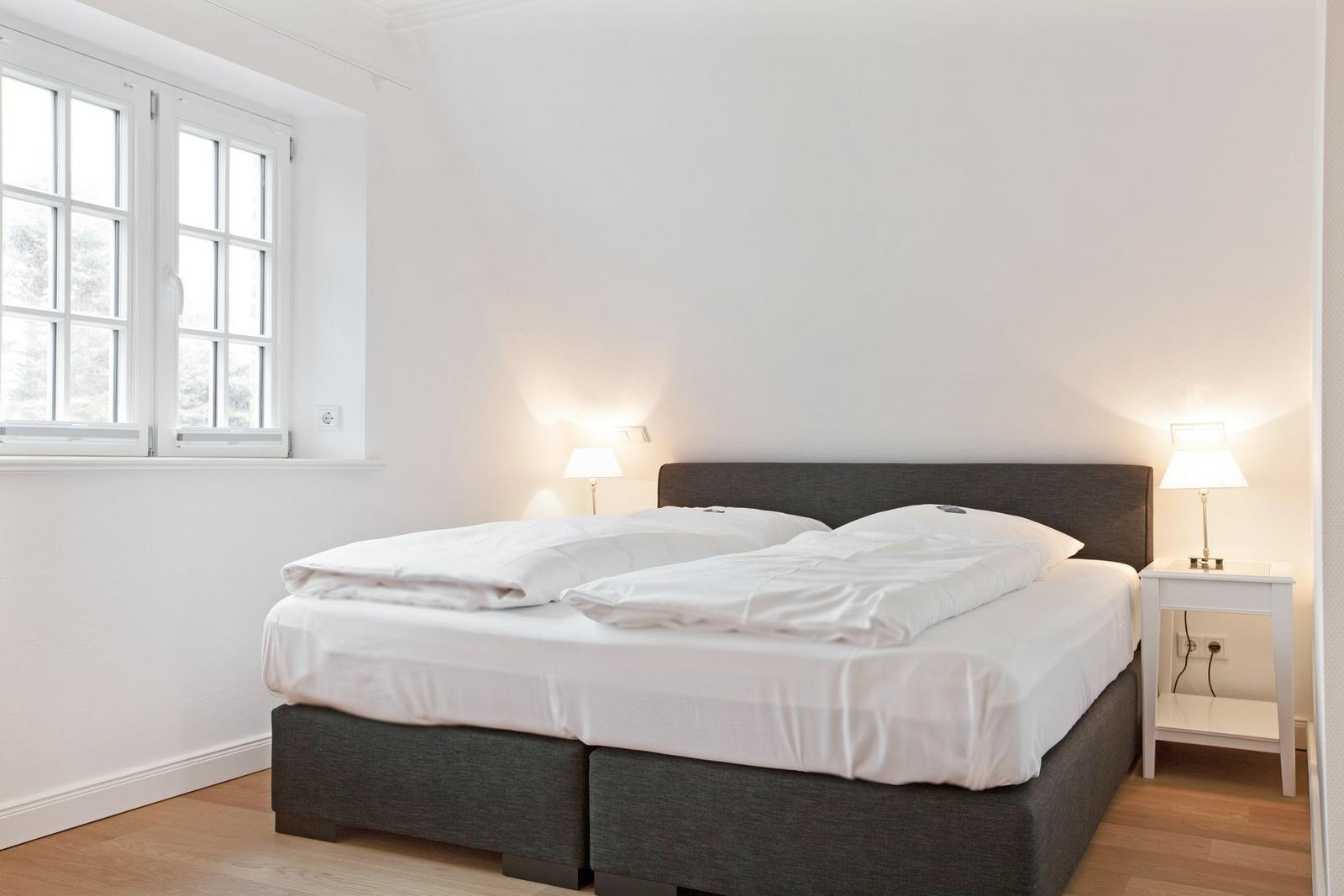 Bedroom with double bed, window, and bedside tables with lamps.