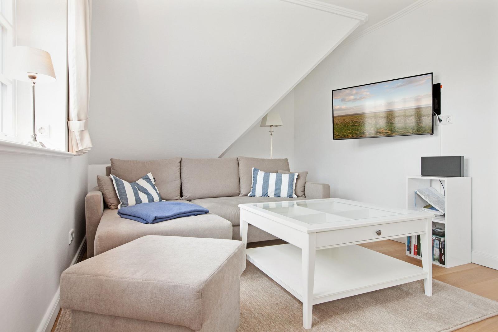 Living room with sofa, coffee table, and TV mounted on the wall.