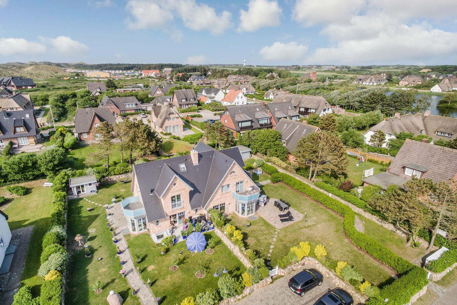 House with large garden and terrace. Surrounded by green areas and other houses.