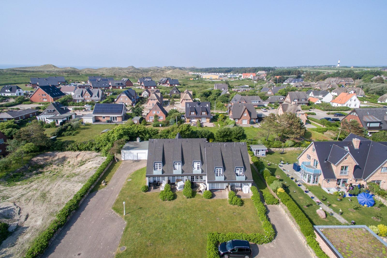 House with large garden and view of coastal landscape with houses and lighthouse.
