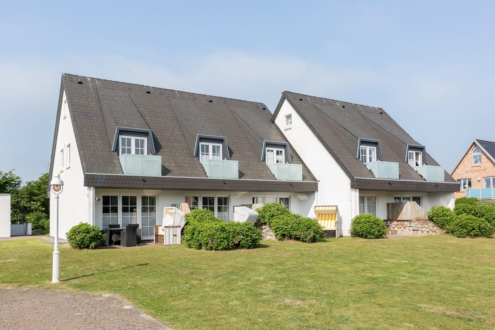 House with dormers and garden. Outdoor shower and lounge chairs.