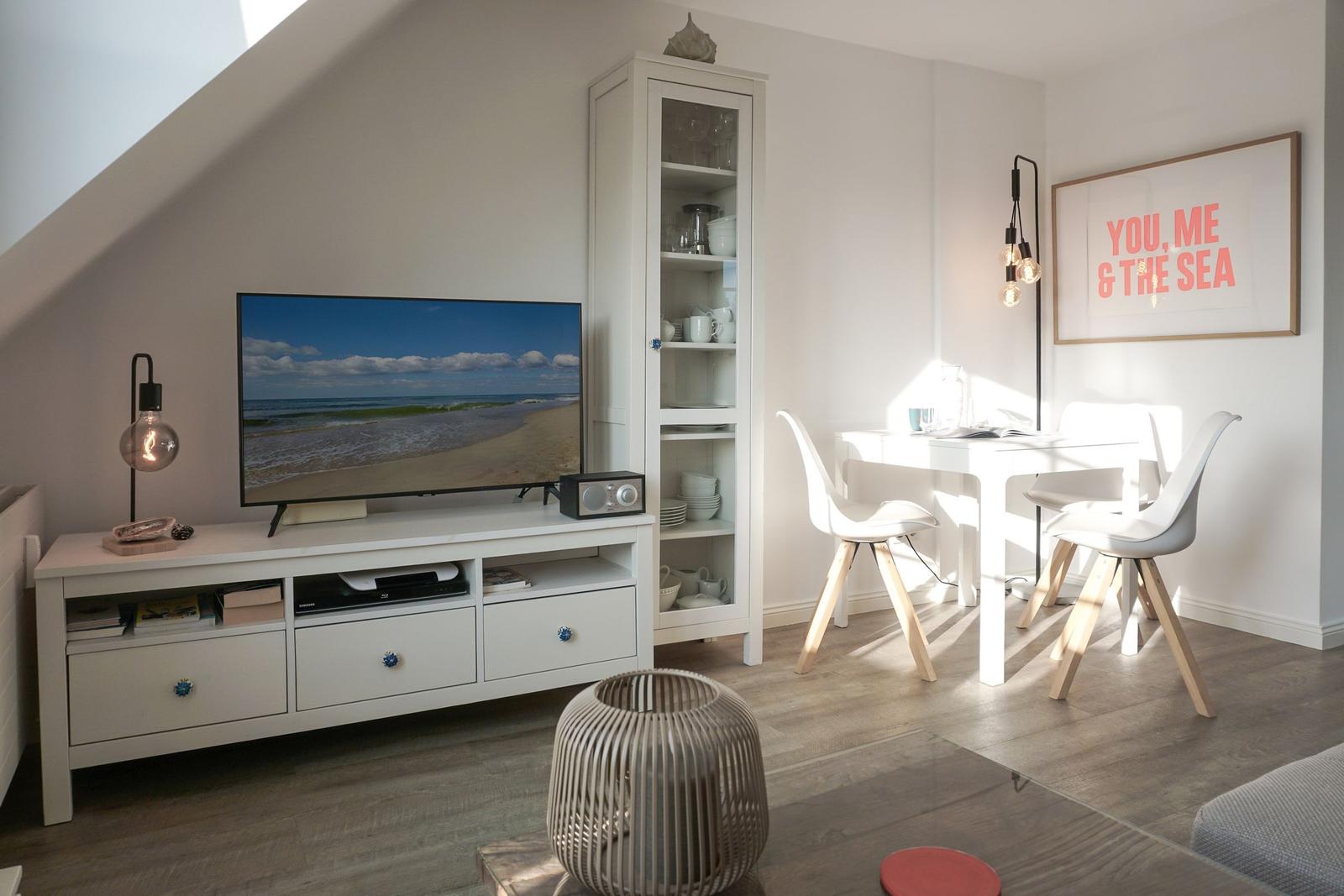 Living and dining area with TV, table, chairs, and cabinet.