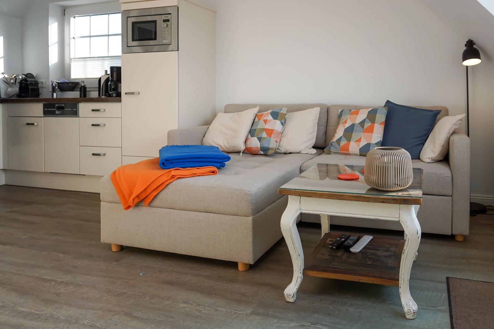 Living area with sofa, coffee table, and kitchen area in the background.
