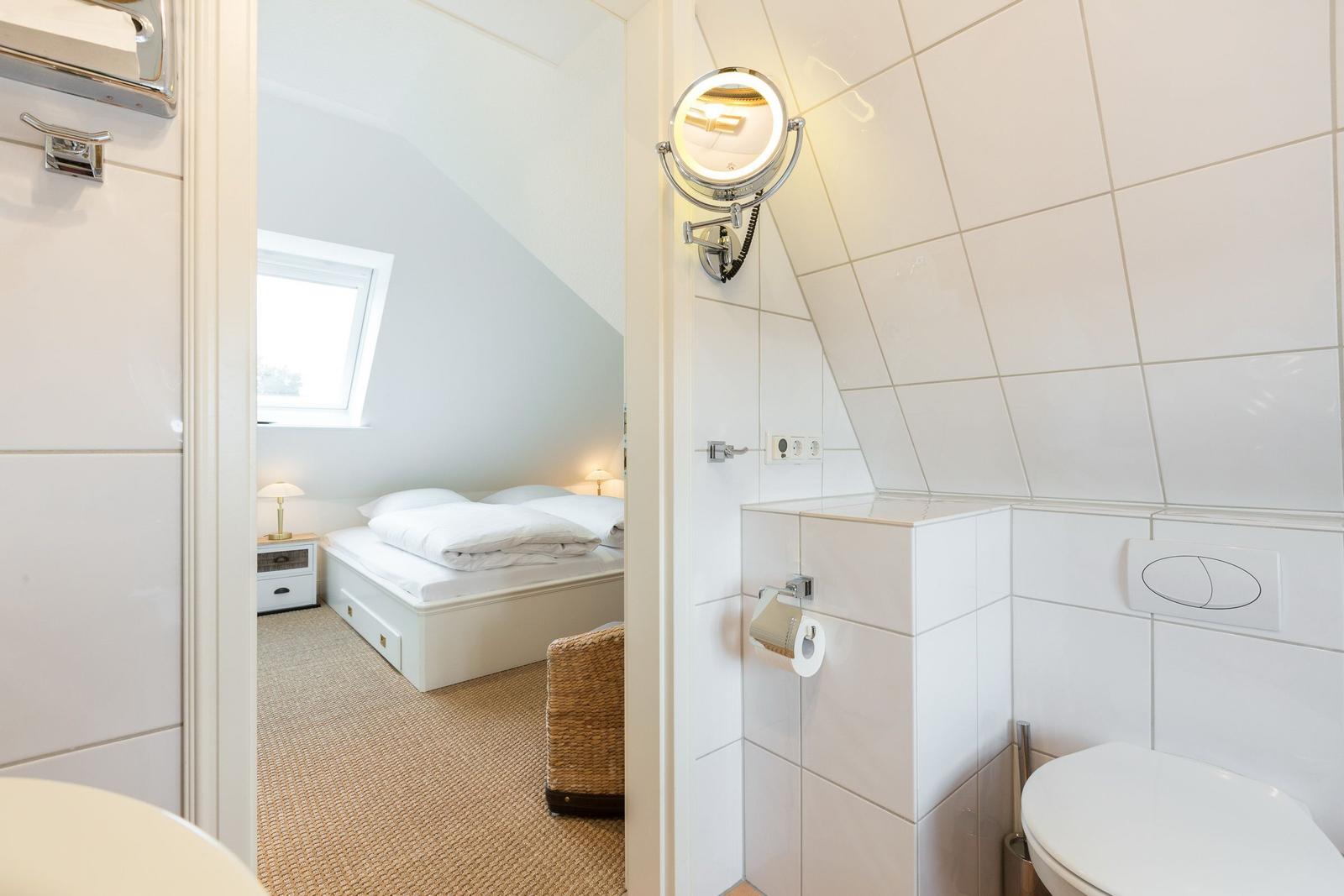 Badezimmer mit Toilette und Spiegel. Durchgang zu Schlafzimmer mit Dachfenster.