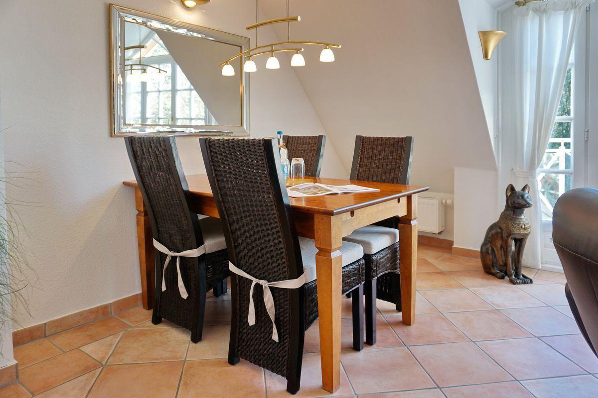 Esszimmer mit Holztisch, vier Stühlen und Spiegel an der Wand.