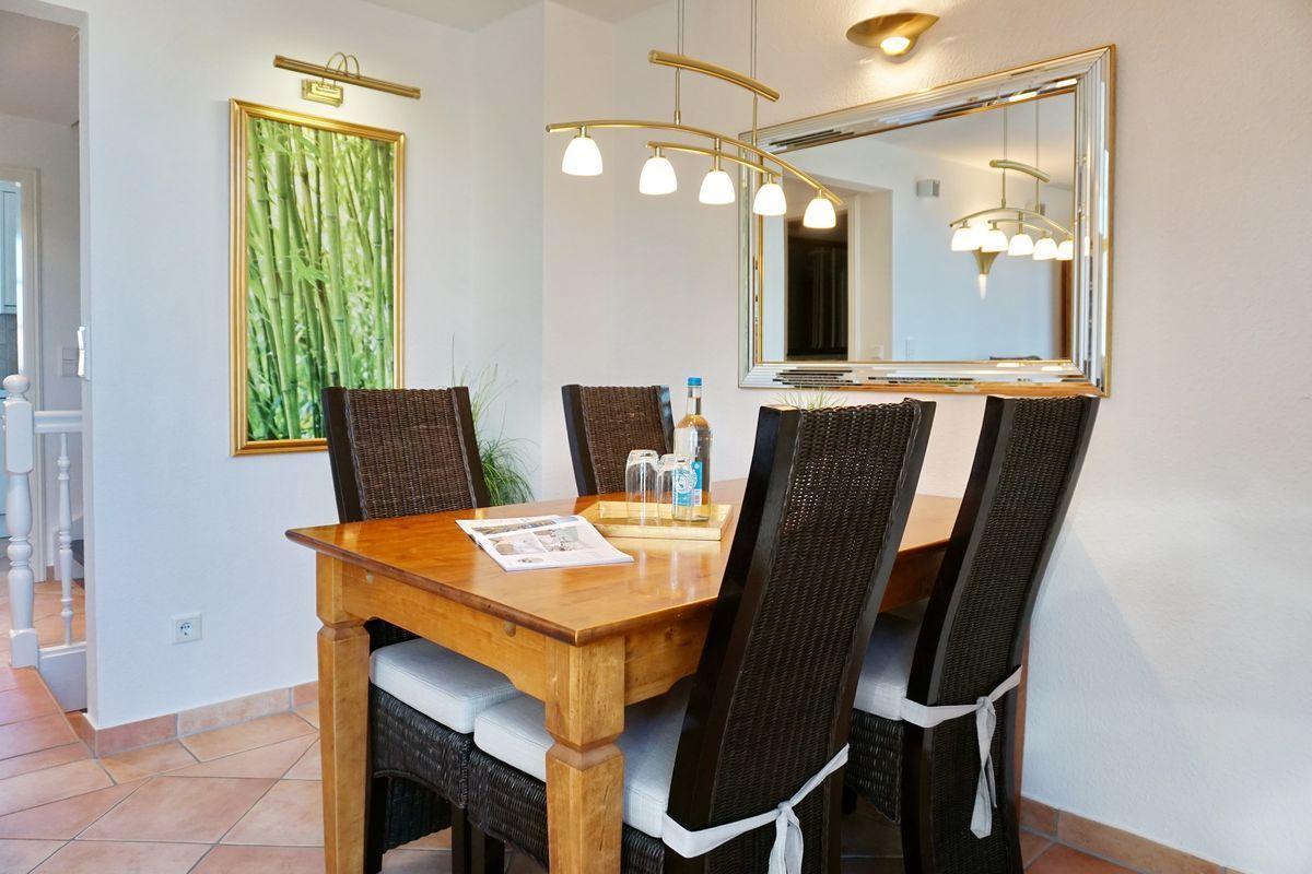 Esszimmer mit Holztisch, vier Stühlen und Wandspiegel