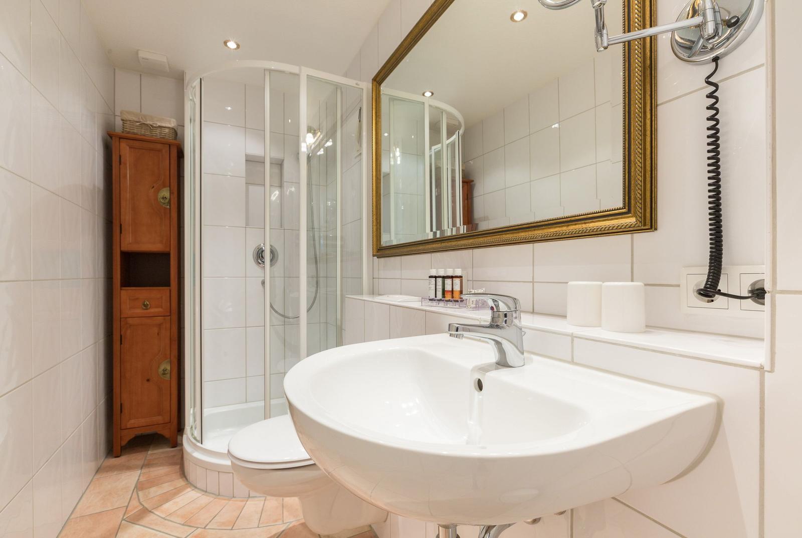 Badezimmer mit Dusche, Waschbecken und Spiegel