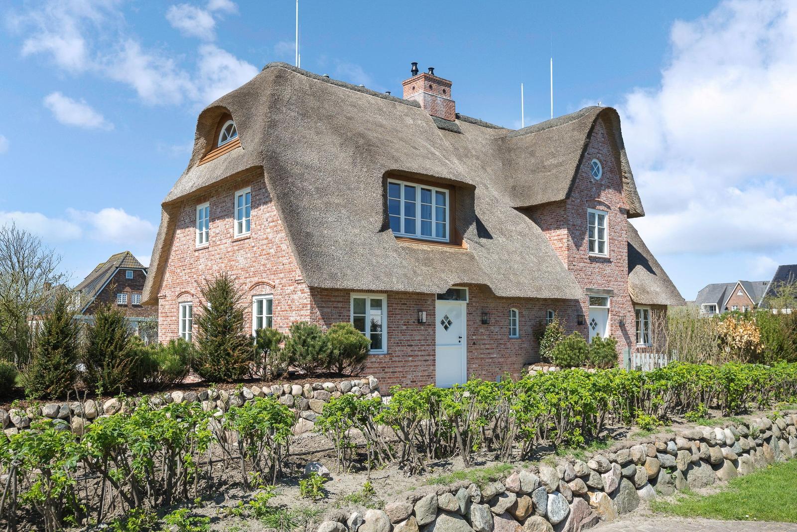 Haus mit Strohdach, Backsteinfassade und Garten