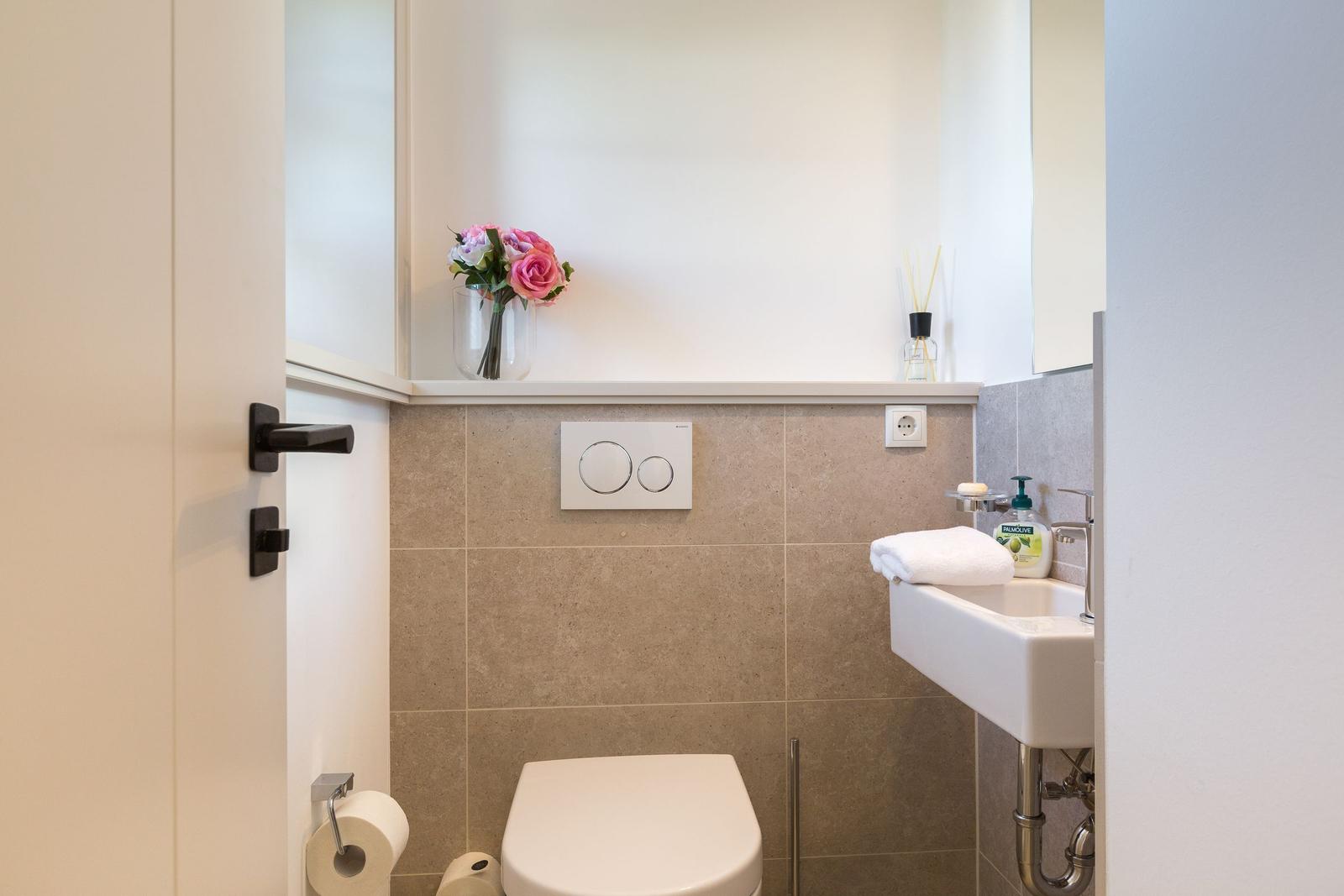 Badezimmer mit Toilette, Waschbecken und Blumenarrangement.