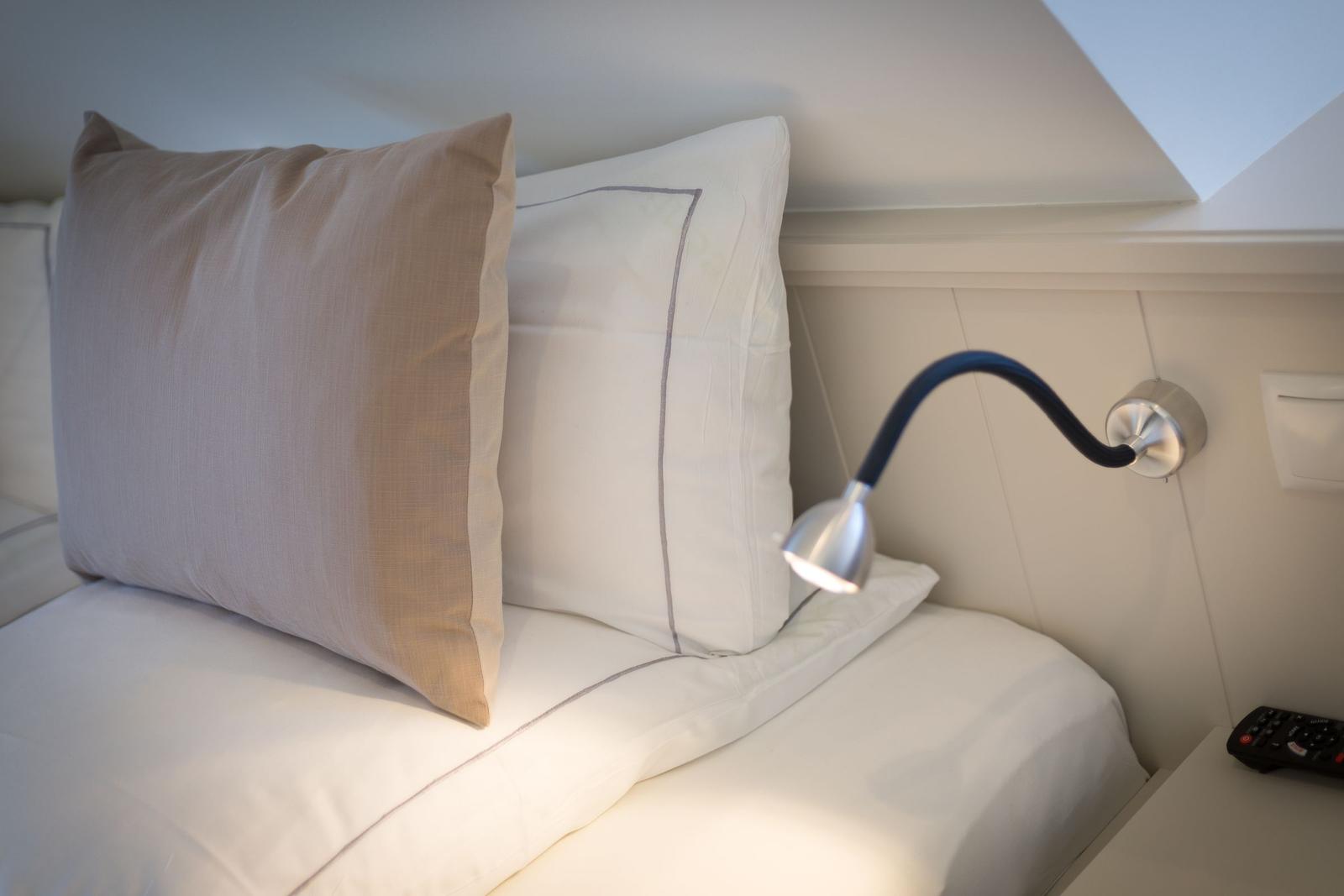 Bettkopf mit Kissen und Wandlampe unter Dachschrägen