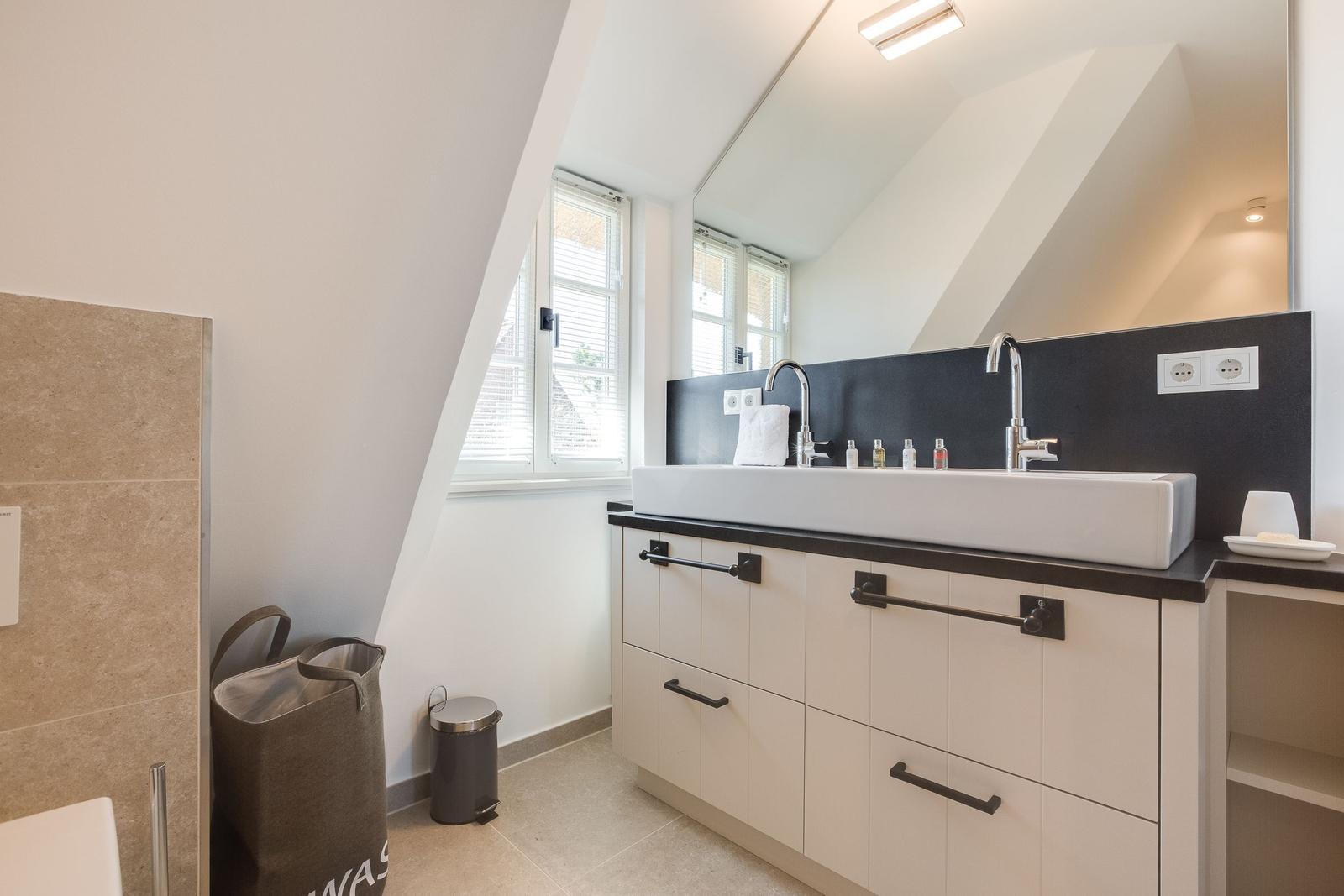 Badezimmer mit Waschbecken, Spiegel und Fenster