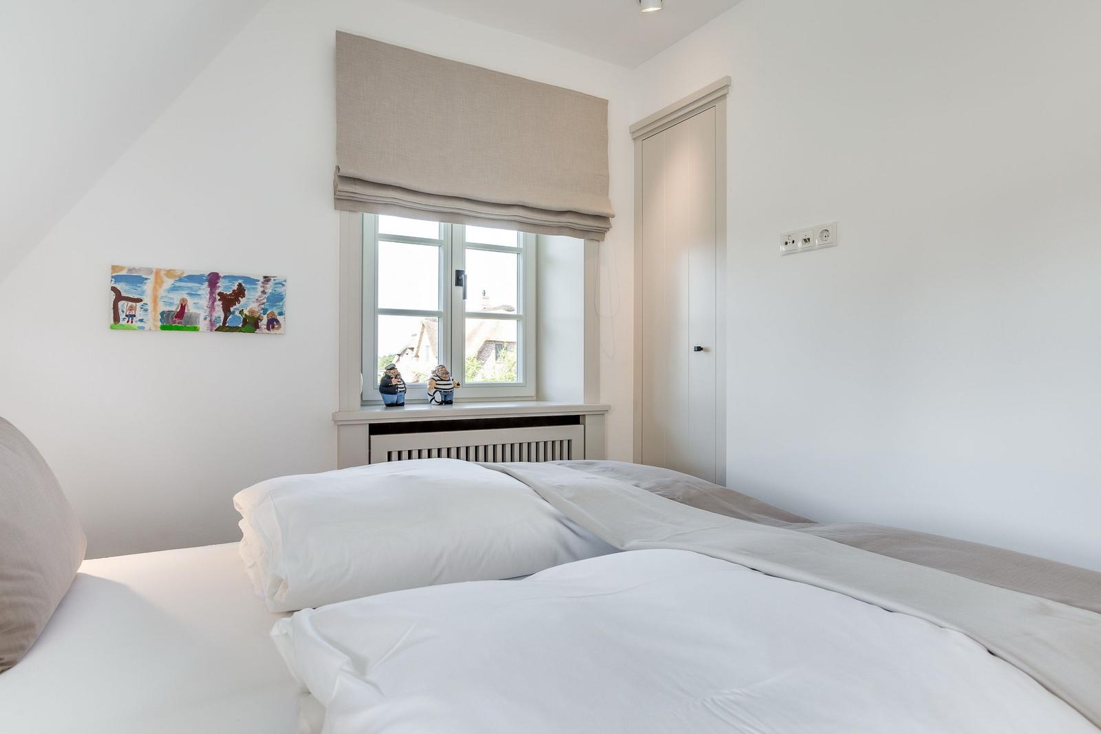Schlafzimmer mit Doppelbett, Fenster und Wandbild.
