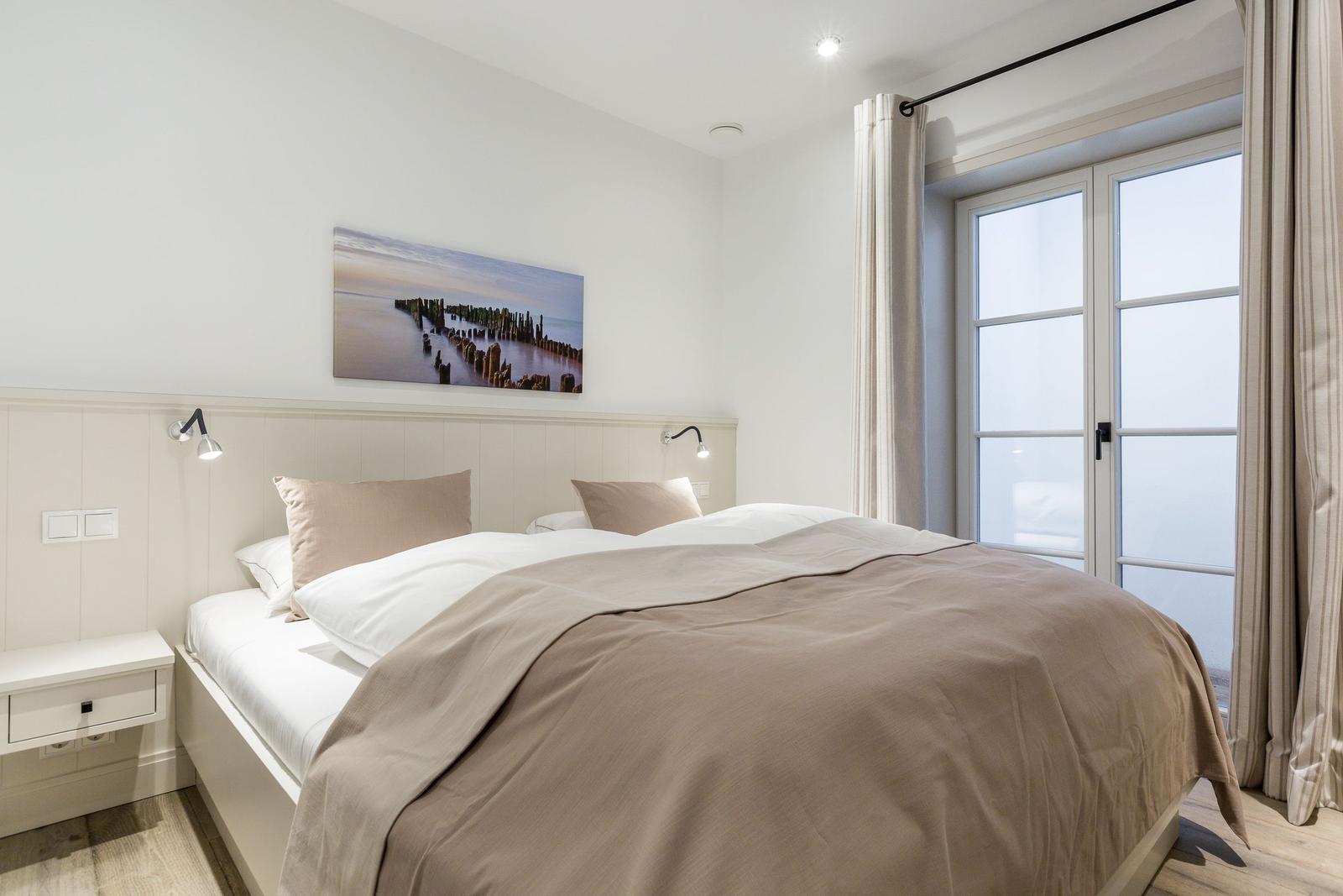 Schlafzimmer mit Doppelbett, Fenster und Wandbild.