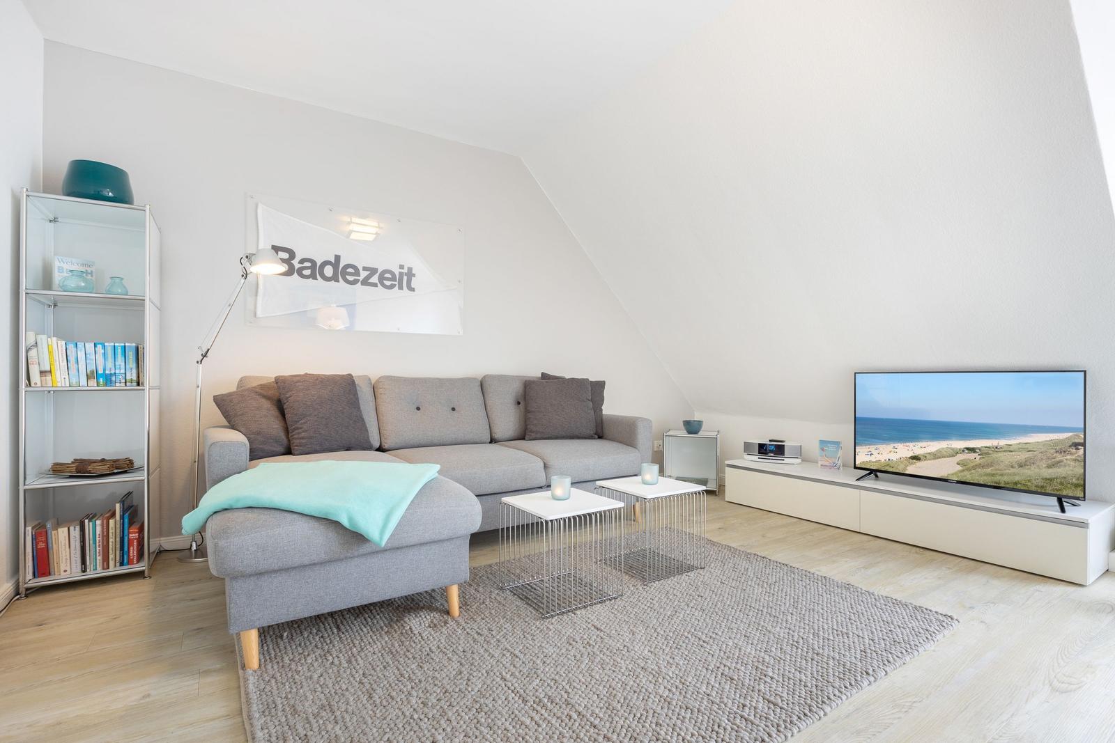 Living room with sofa, TV, and bookcase under sloped ceiling.