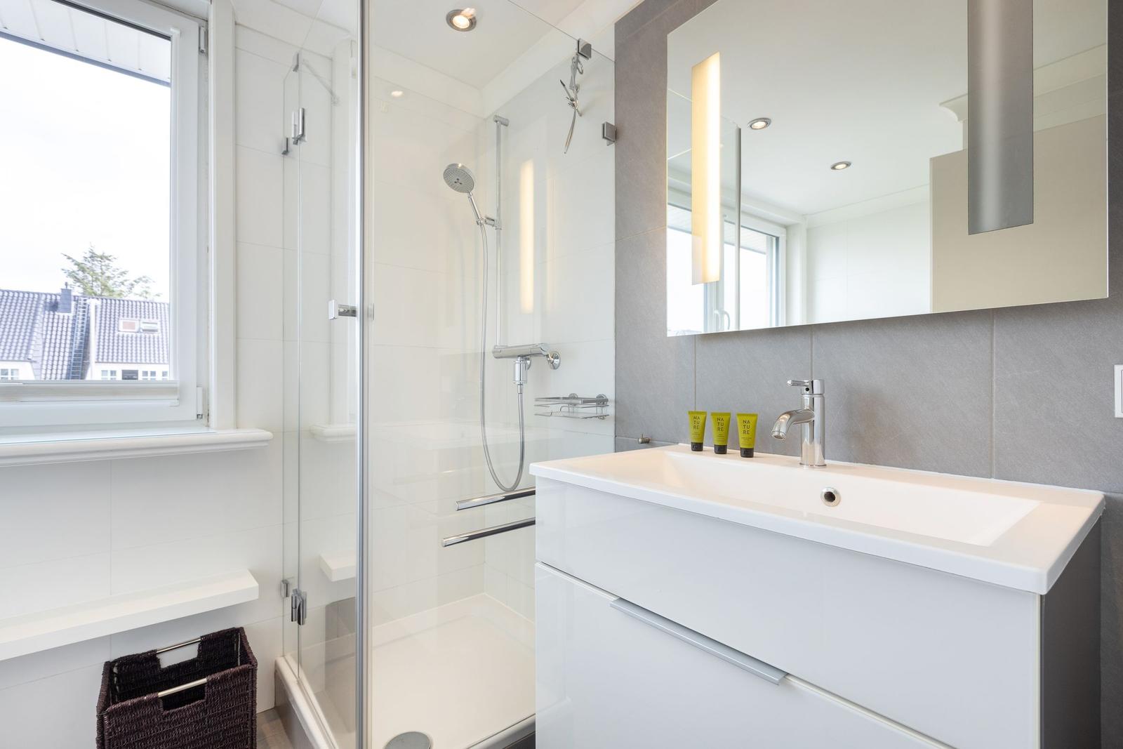 Bathroom with shower, sink, and window.