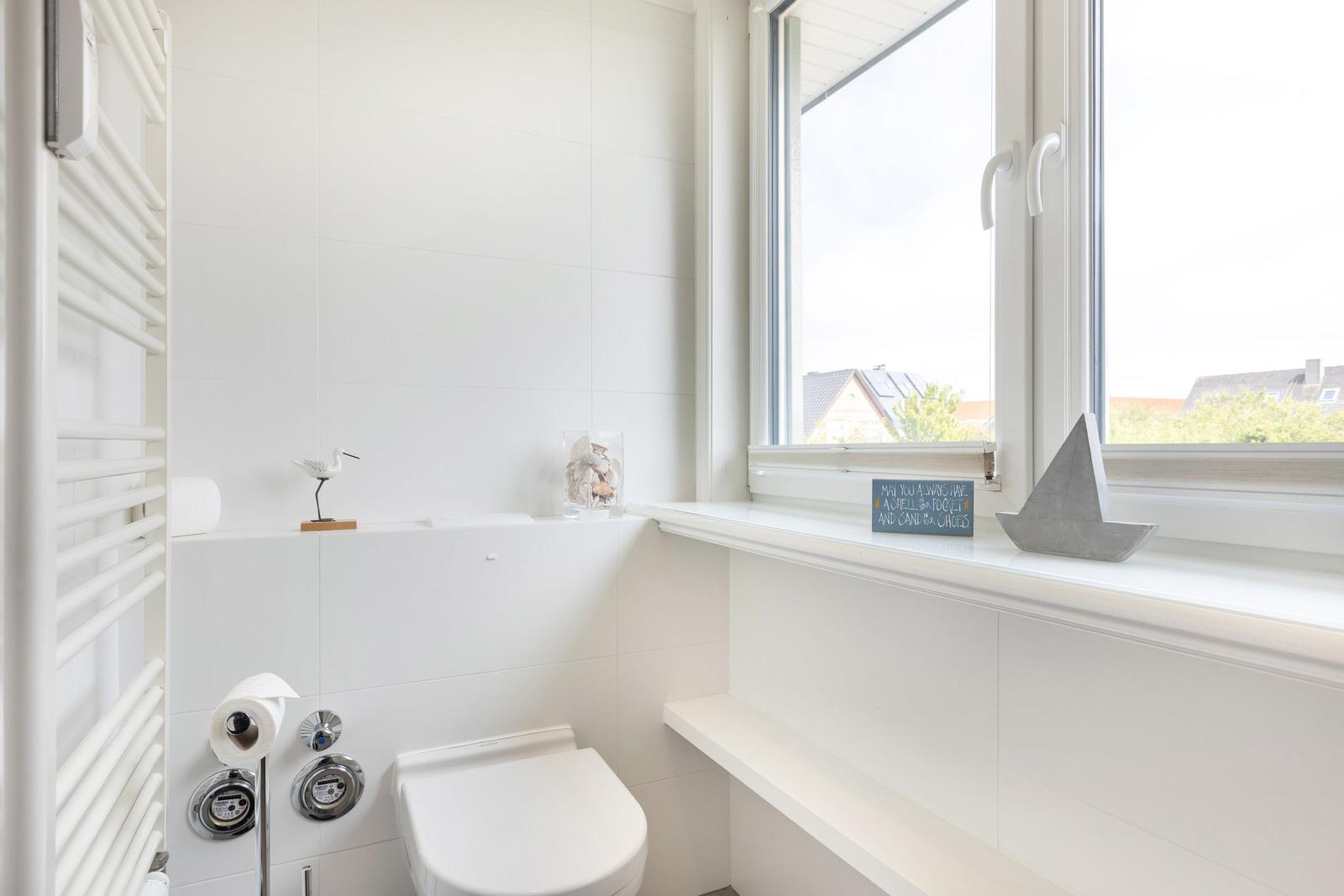 Bathroom with toilet, heater, and window with view.