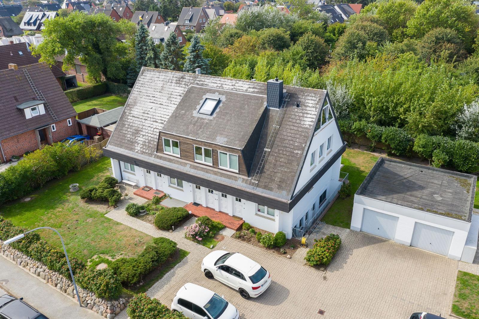 House with attic terrace, garden, and garage. Two white cars parked on the yard.