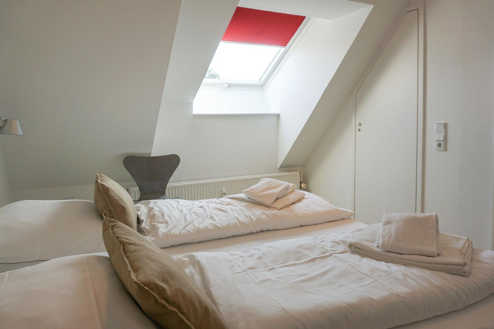 Bedroom with sloped ceiling, skylight, and bed with towels.