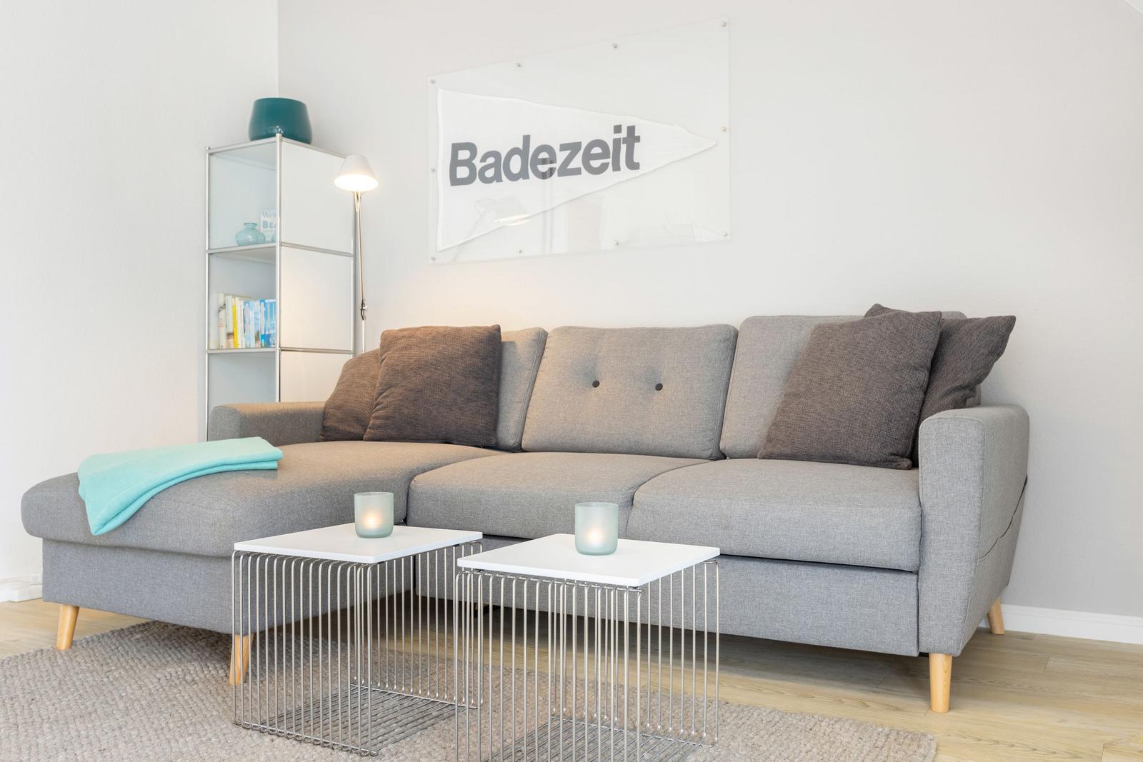 Gray sofa with cushions and two tables against wall with flag.
