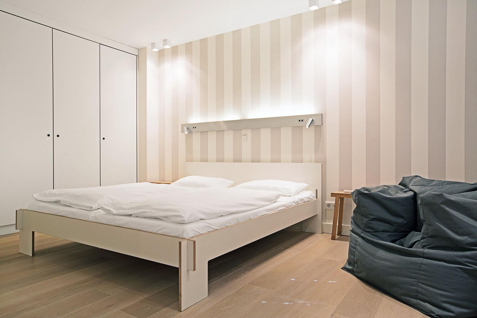 Schlafzimmer mit Bett, Kleiderschrank und Sitzgelegenheit.