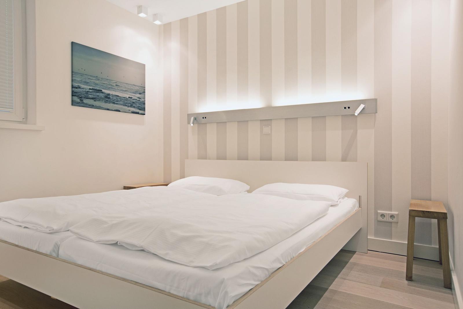 Schlafzimmer mit Bett, Wandbild und Streifenwand