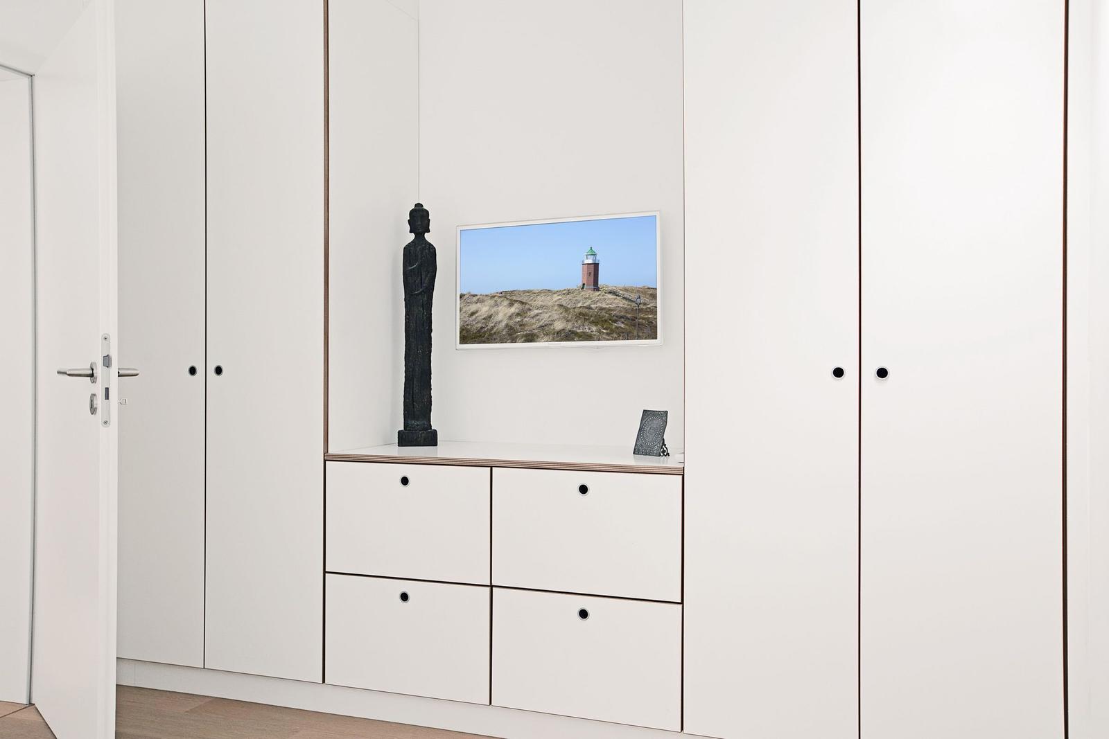 Schlafzimmer mit weißen Schränken und Bildern an der Wand.