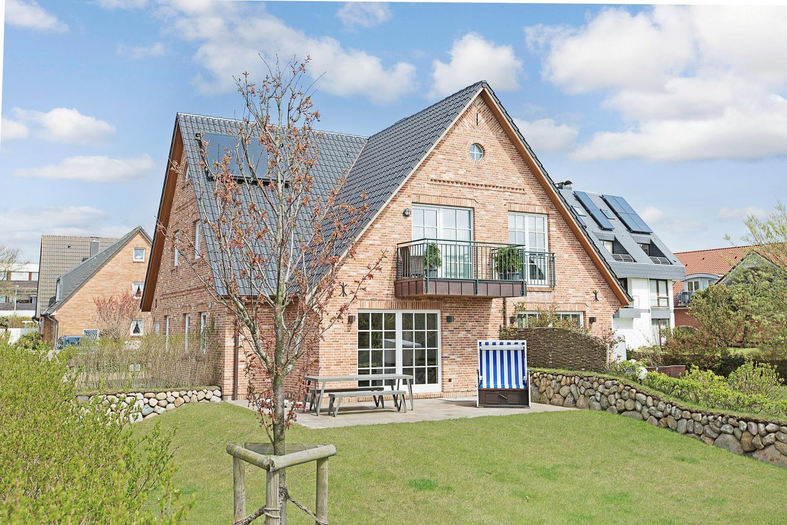 Ein Haus mit Terrasse, Garten und Sonnenschutz.
