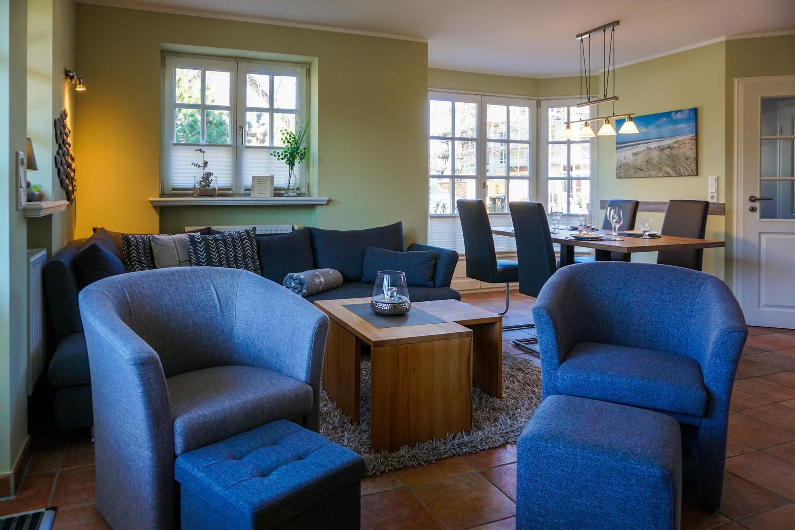 Wohn- und Essbereich mit blauen Sesseln, Sofa und Holztisch.