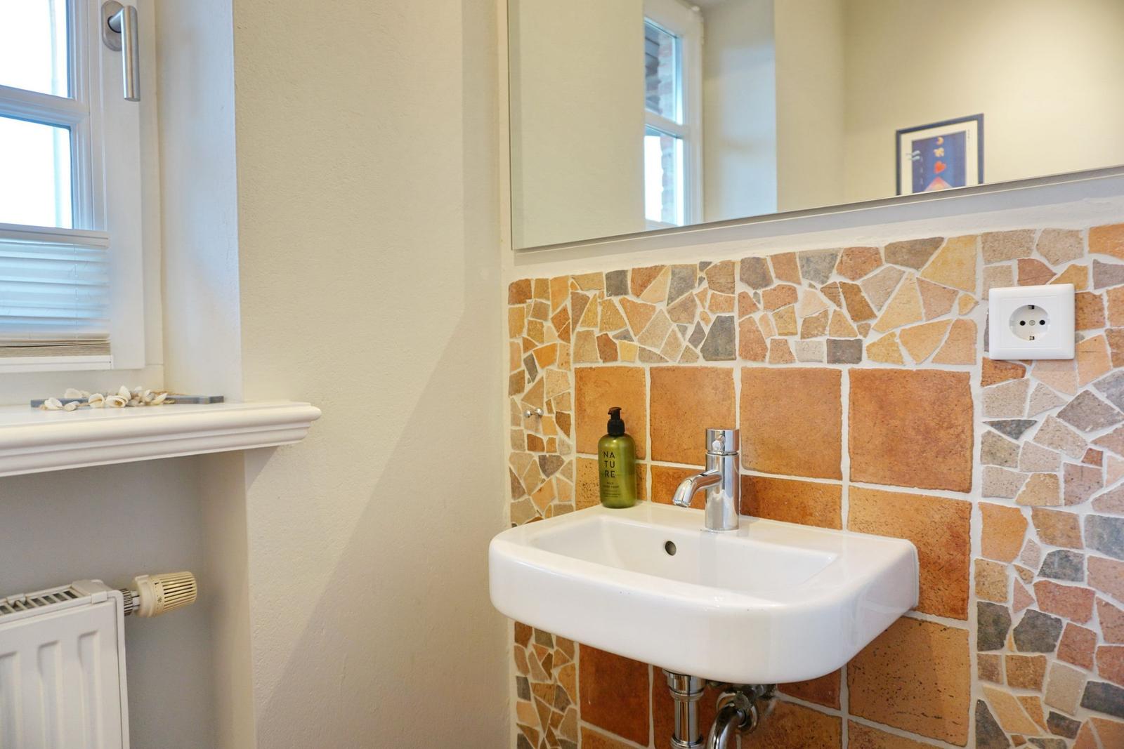 Waschbecken mit Steinwand, Spiegel und Fenster
