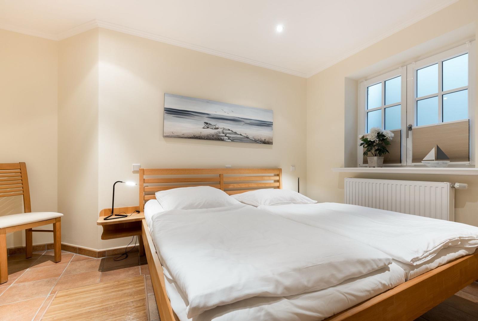 Schlafzimmer mit Doppelbett, Holzgestell und Fenster mit Blick.