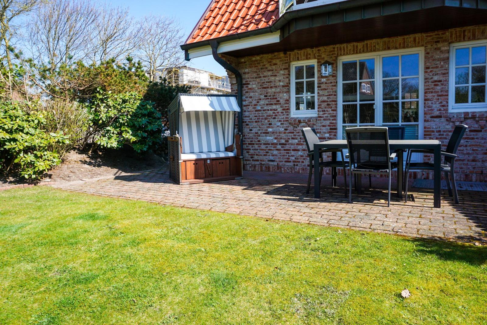 Hinterhof mit Terrasse, Garten, Liege und Tisch mit Stühlen.