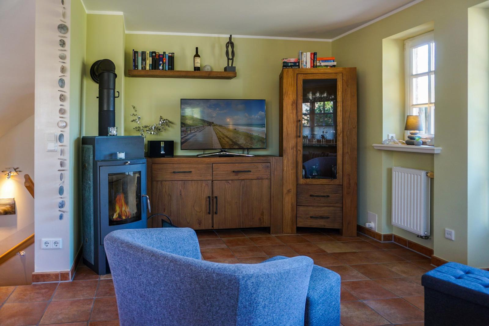 Wohnzimmer mit Kamin, Fernseher und Holzmöbeln.