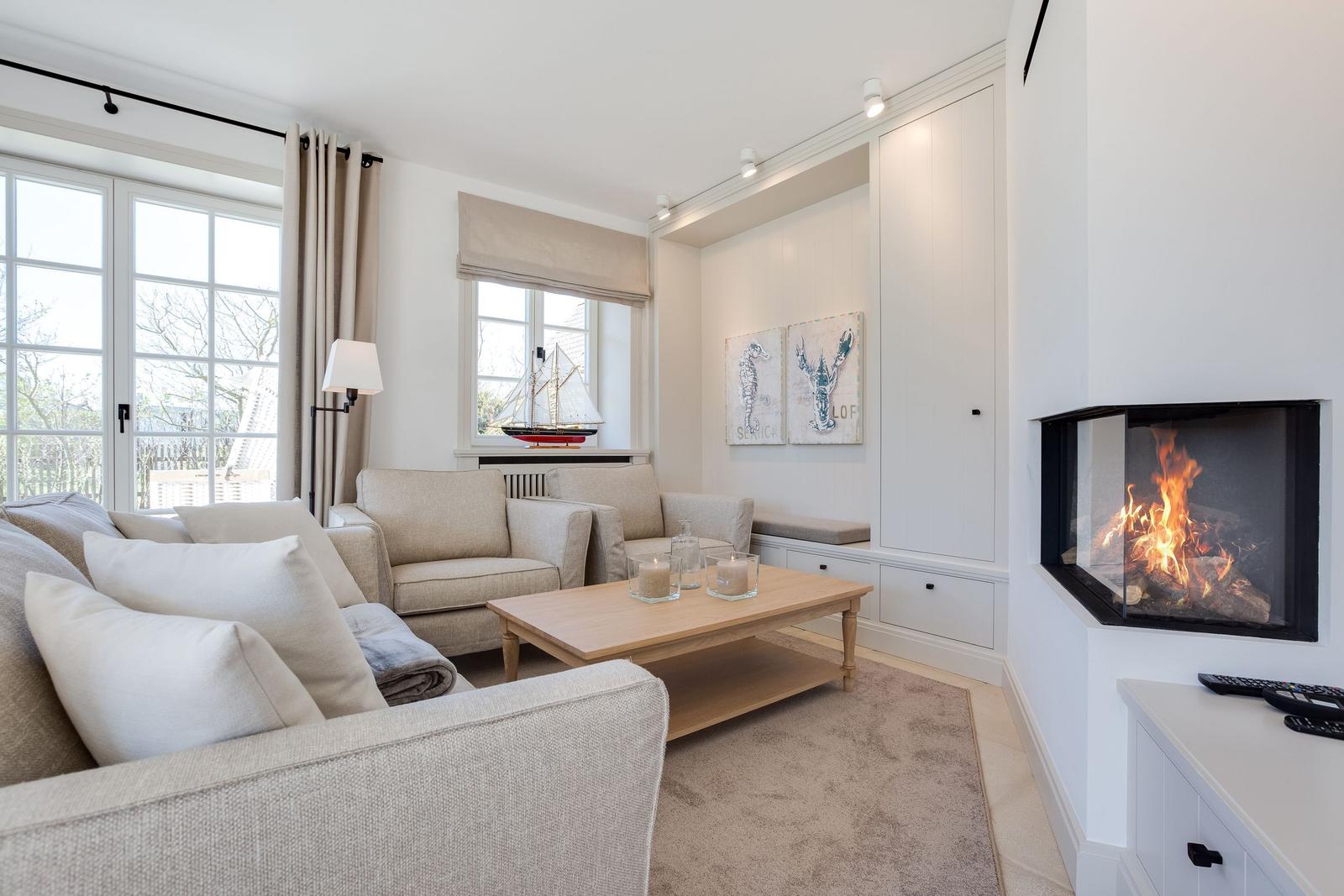 Wohnzimmer mit Kamin, Sofa, Tisch und Fenstern.