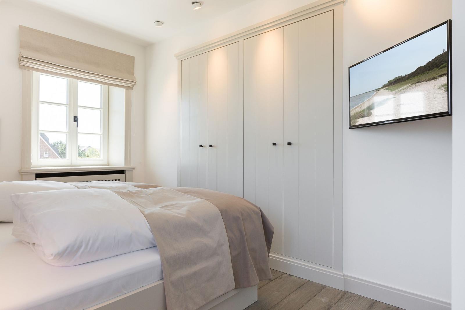 Schlafzimmer mit Bett, Kleiderschrank und Wandbild