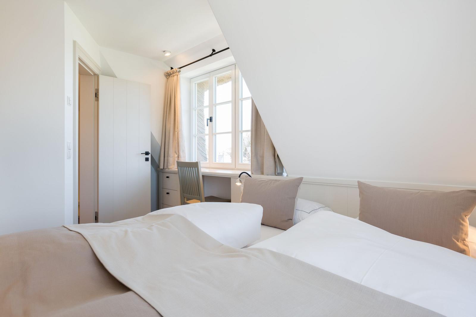 Schlafzimmer mit Bett, Schreibtisch und Fenster